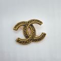 Broche Chanel en plaqué or et résine noire : deux C entrelacés élégants